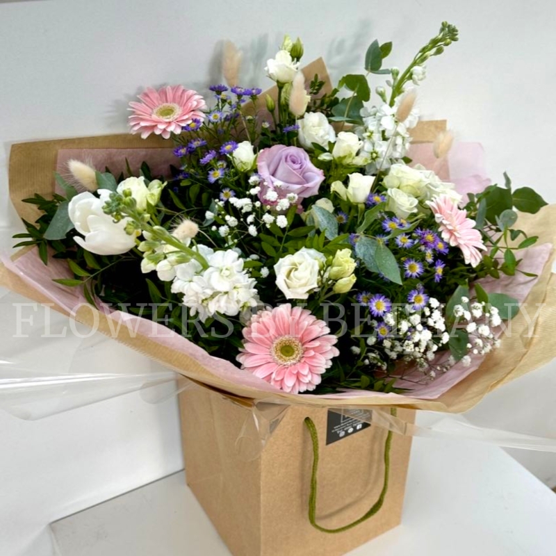 Hand tied bouquet in soft pinks, lilac and white, including roses, stocks, germini, bunny tail and other mixed varieties. 