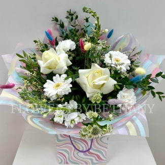 All white bouquet with a whimsical twist, pastel bunny tails dispersed through the bouquet. Wrapped in a wavy print bag and cellophane hand tied in water. 