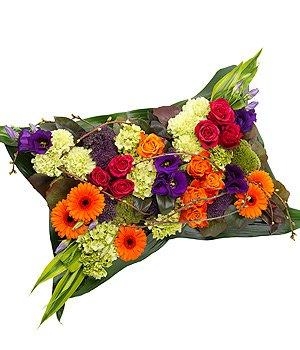 Vibrant mixed pillow funeral tribute including roses, germini and mixed foliage. 