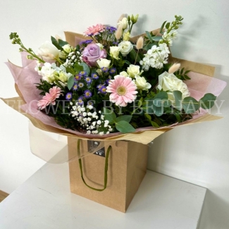 Hand tied bouquet in soft pinks, lilac and white, including roses, stocks, germini, bunny tail and other mixed varieties. 