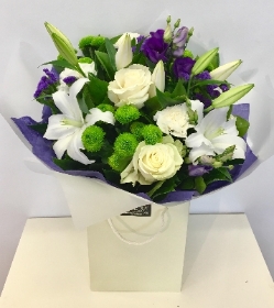 Hand tied bouquet of purple, white and vivid green seasonal flowers. 