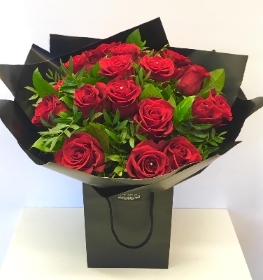 Hand tied bouquet of 18 luxury red roses gift wrapped in cellophane and placed in our signature bag. 
