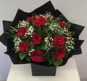 12 Red roses and white gypsophila with complimenting foliage in our signature wrap and gift bag. 