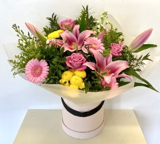 Hand tied in luxury hat box including roses lilies and other mixed pink and yellow flowers. 