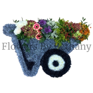 Wheelbarrow funeral tribute, with overflowing florals in mixed vibrant tones. 