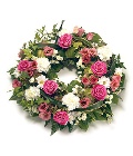Pink and white loose funeral wreath tribute including roses, carnations and chrysanthemum. 